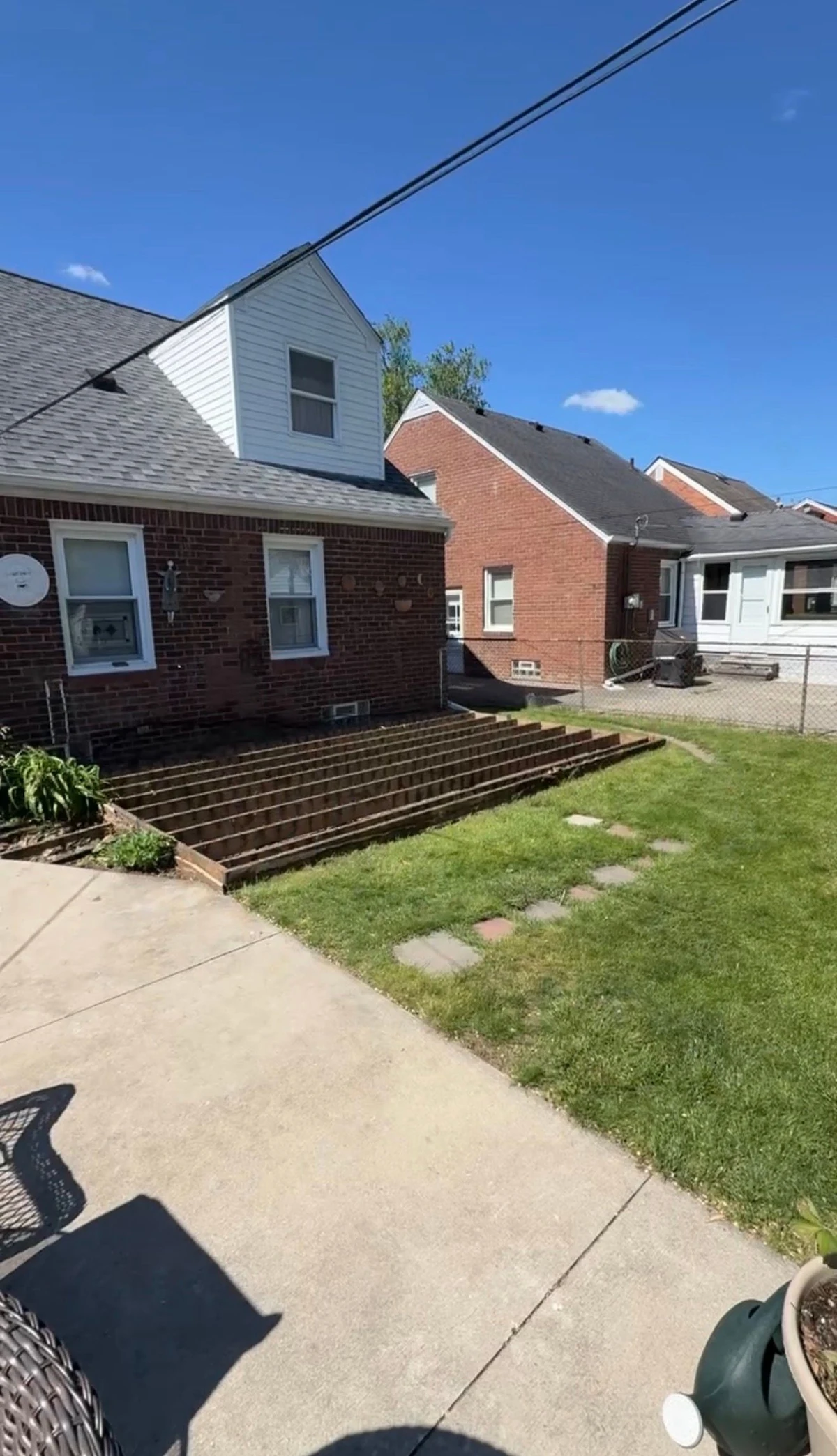 Bare deck framing left in place along the house after the wood boards were removed in Grosse Pointe Woods, with the lawn and concrete area cleared